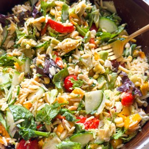a bright and vibrant bowl of salad with orzo, fresh vegetables and spinach